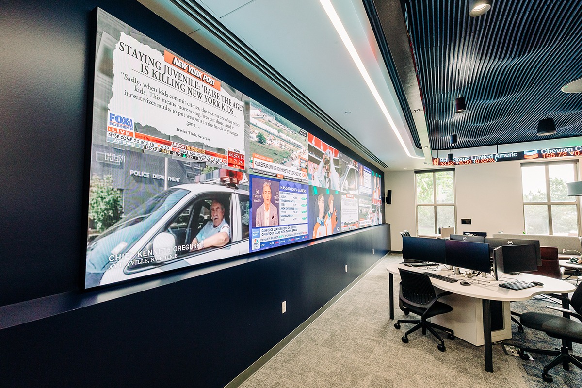 large display wall with multiple TVs showing different news broadcasts